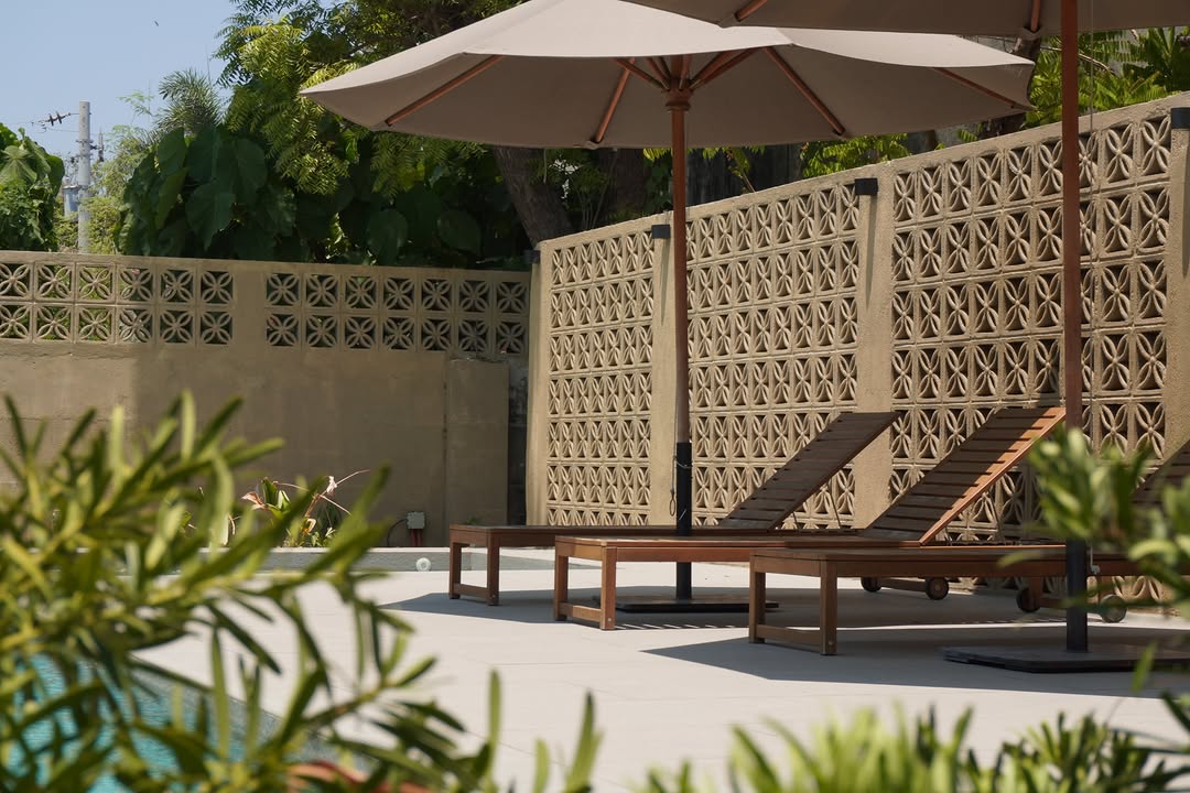 Pool area with wooden loungers and heritage breeze block wall